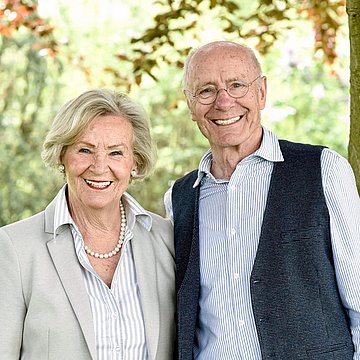 Zwei ältere Menschen, die lächelnd in die Kamera schauen